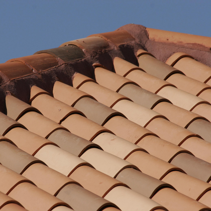 Terracotta roof tiles with varying shades against a clear blue sky.