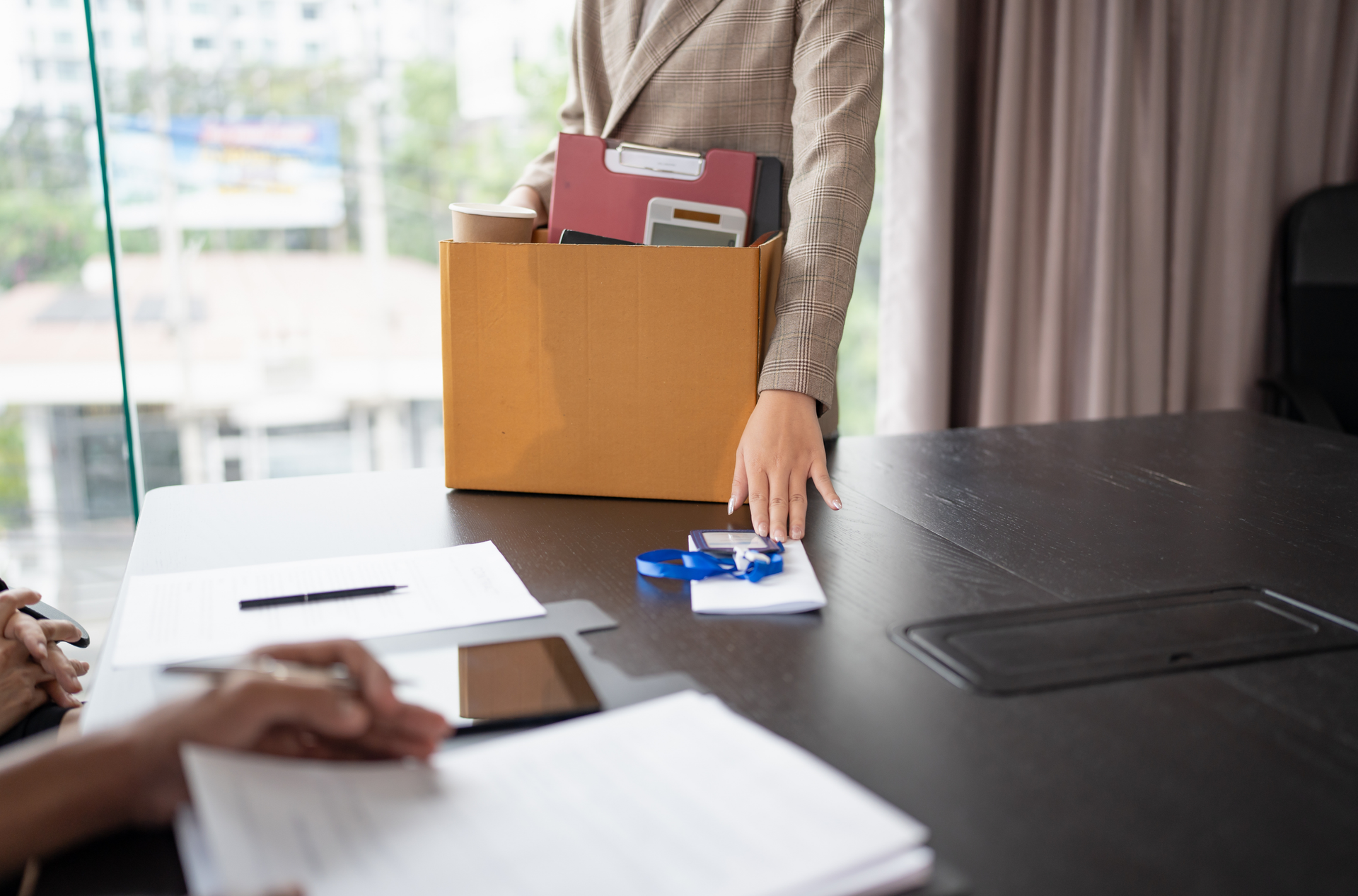Person handing in their badge and has a box of their items.