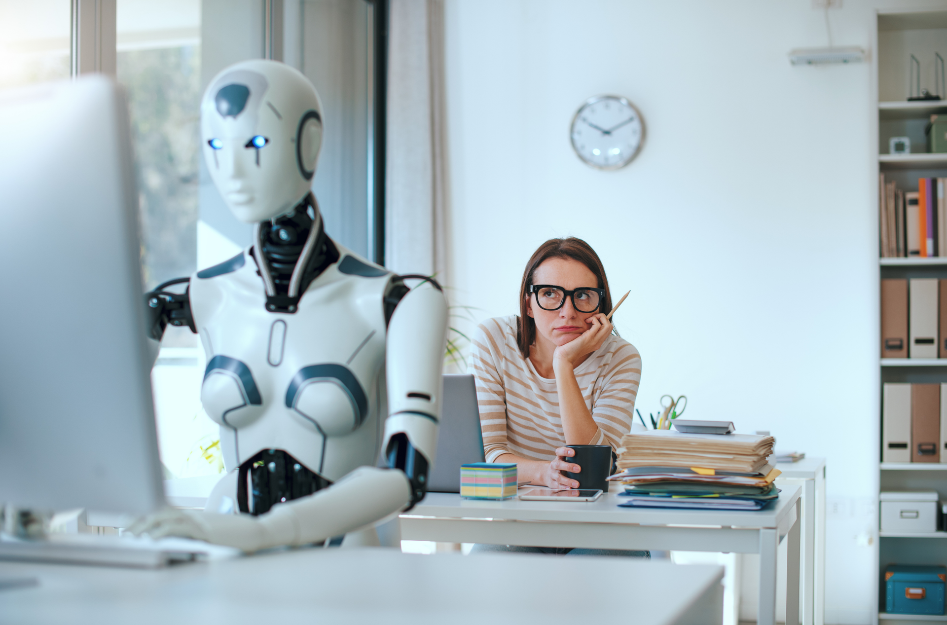 Woman looking at a robot sitting at a desk