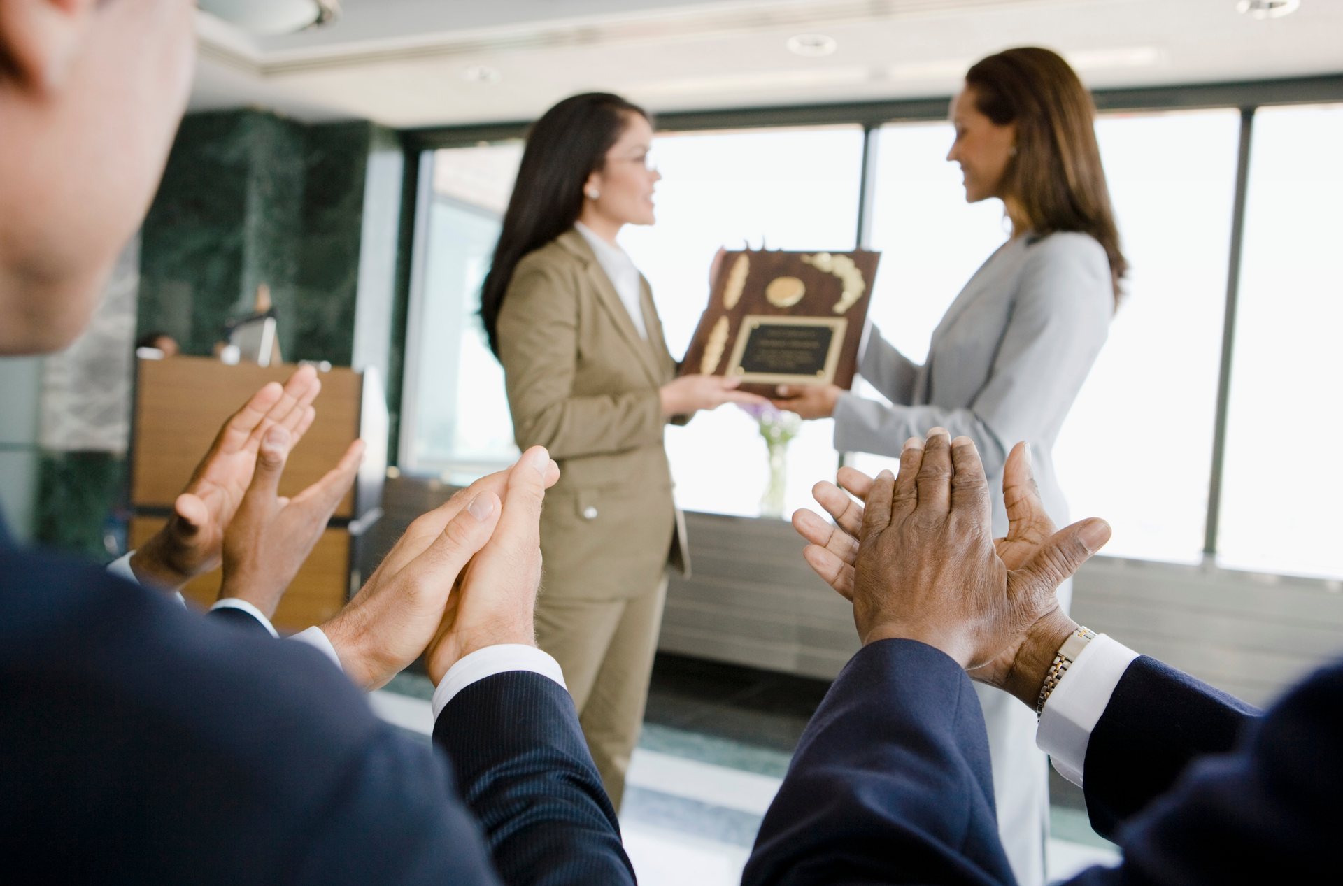 Two people holding an award while other people celebrate