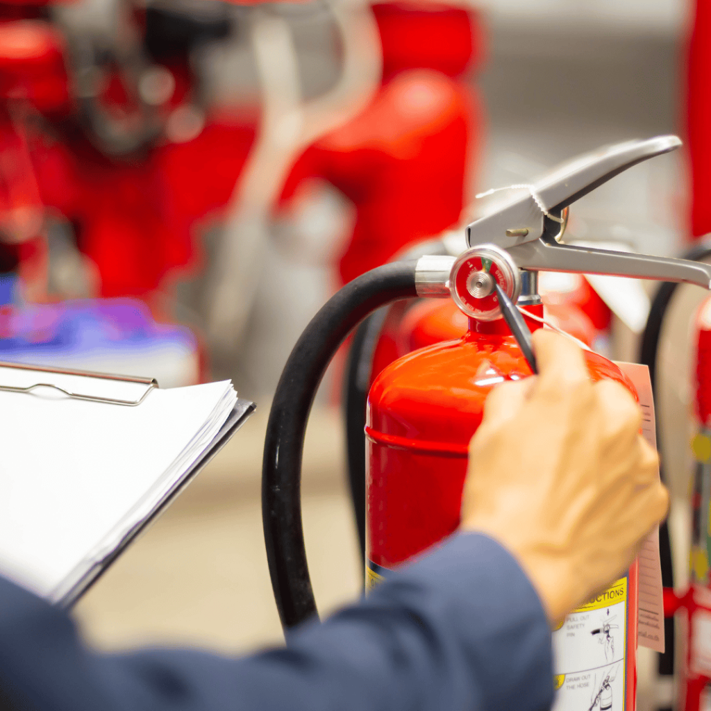 Person inspecting a red fire extinguisher with a clipboard in a warehouse setting.