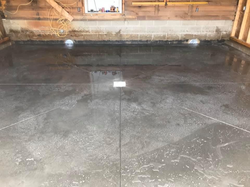 A concrete floor in a garage with a window in the background.