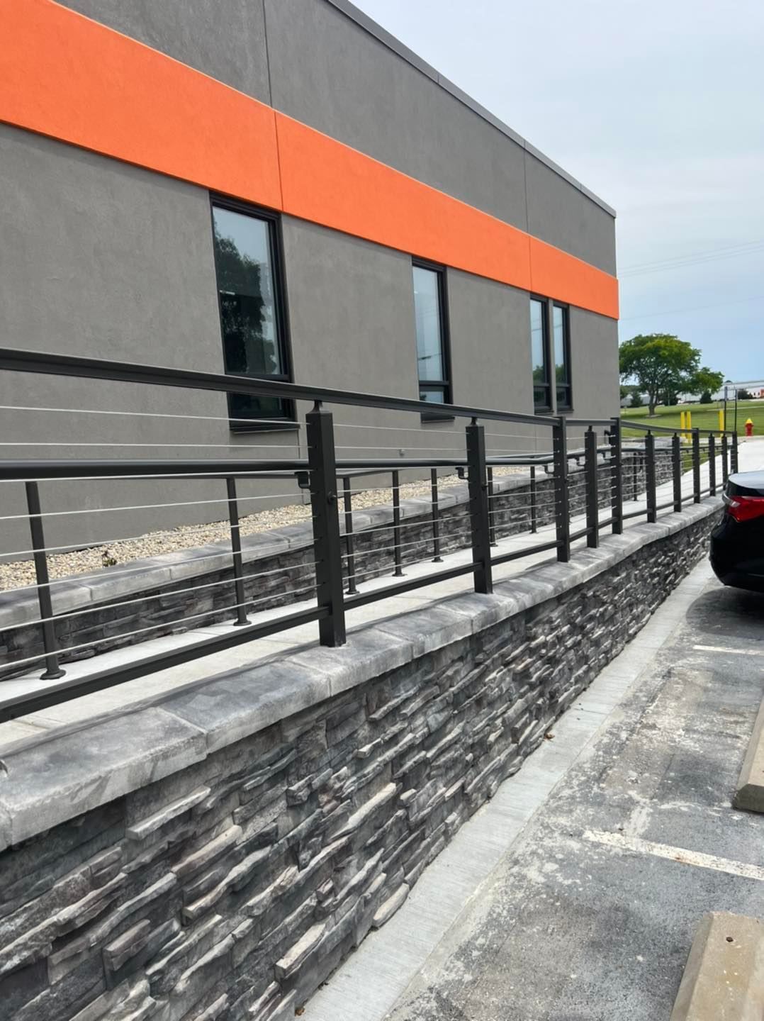 A car is parked in front of a building with a fence around it