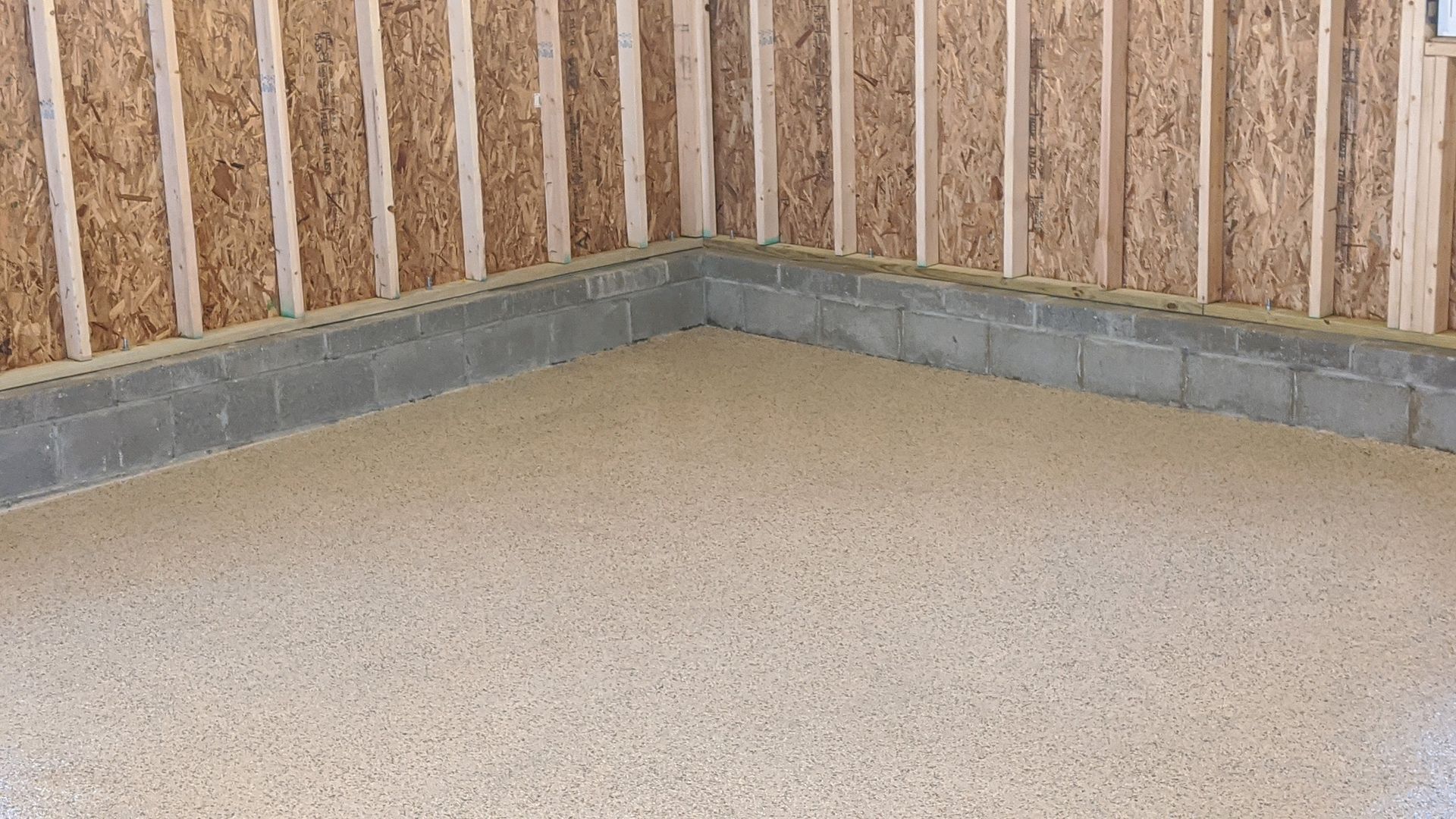 A corner of a garage with a concrete floor and wooden walls.