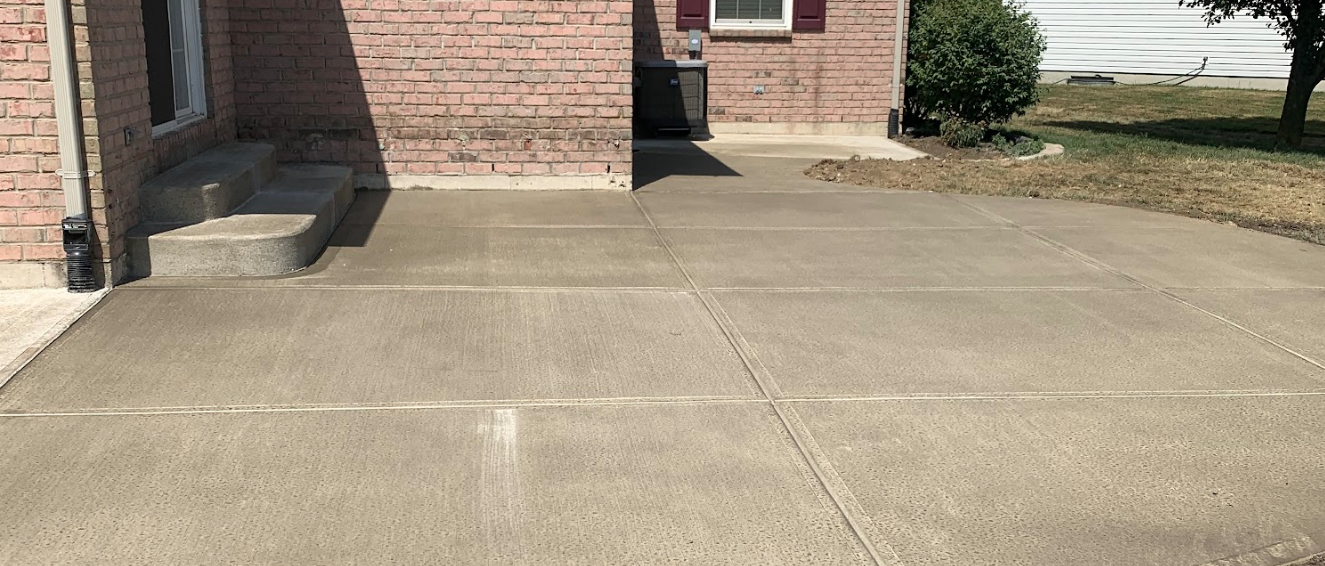 A brick house with a concrete driveway in front of it.