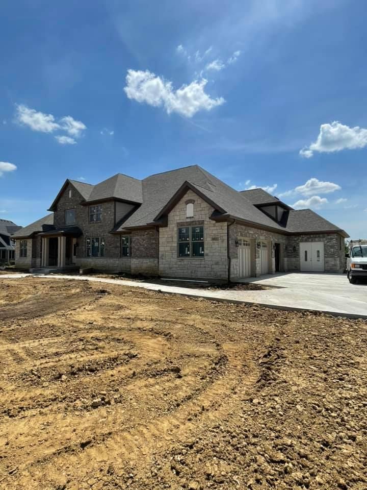 A large brick house is sitting on top of a dirt field.