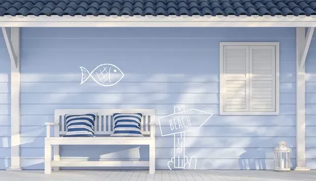 White bench with striped pillows under a blue house awning, fish drawing, arrow sign, and window.