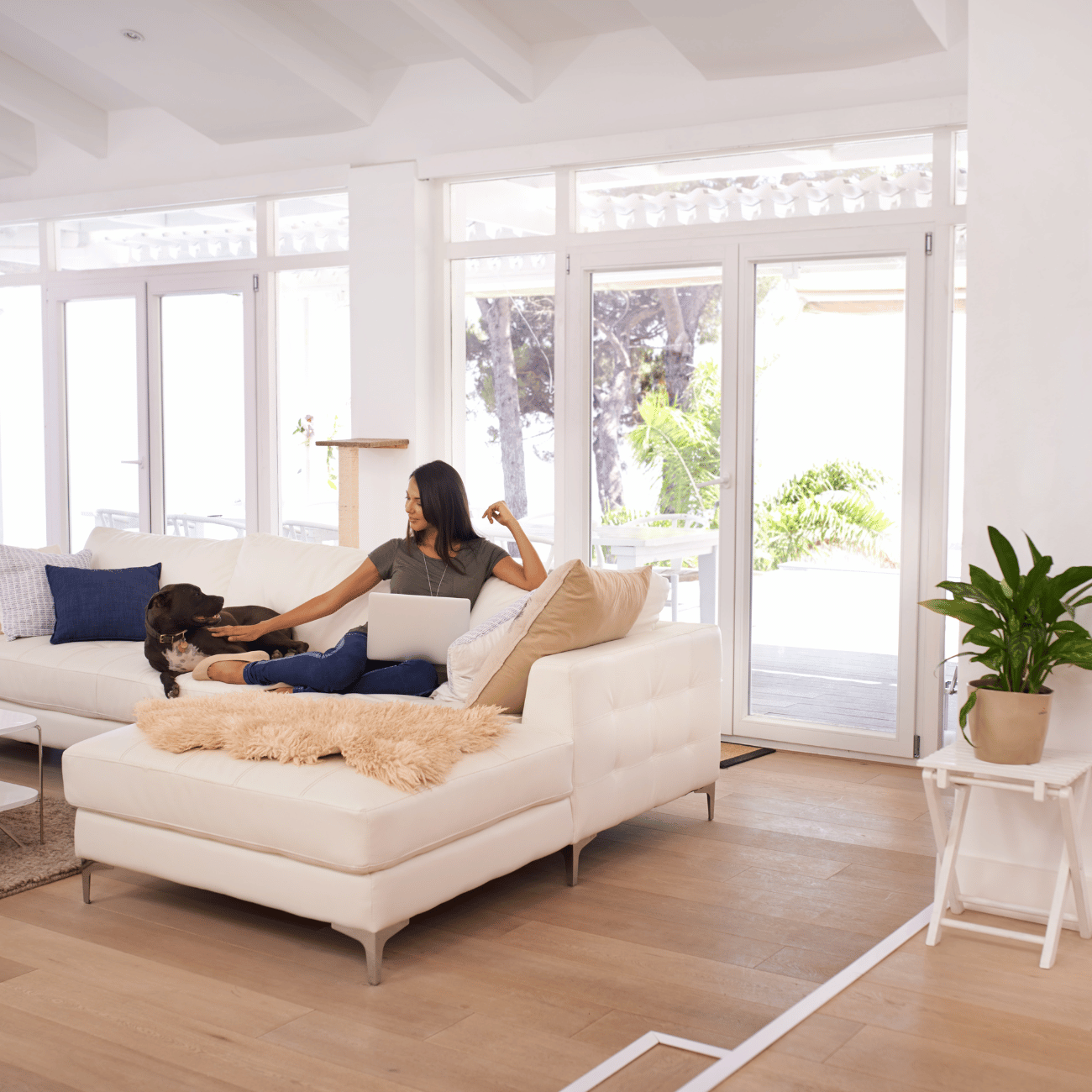 A woman is sitting on a couch in a living room with a dog.