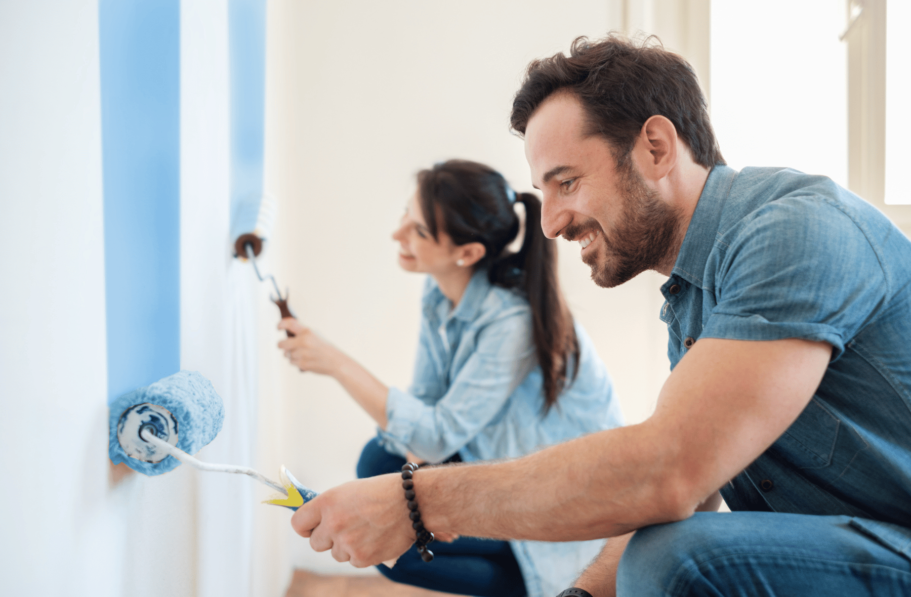 A man and a woman are painting a wall together.