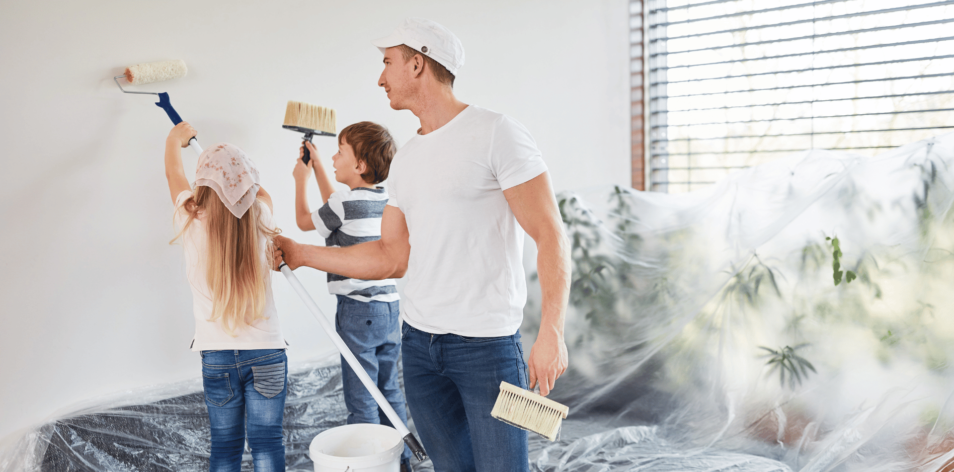 Man painting a wall with his children