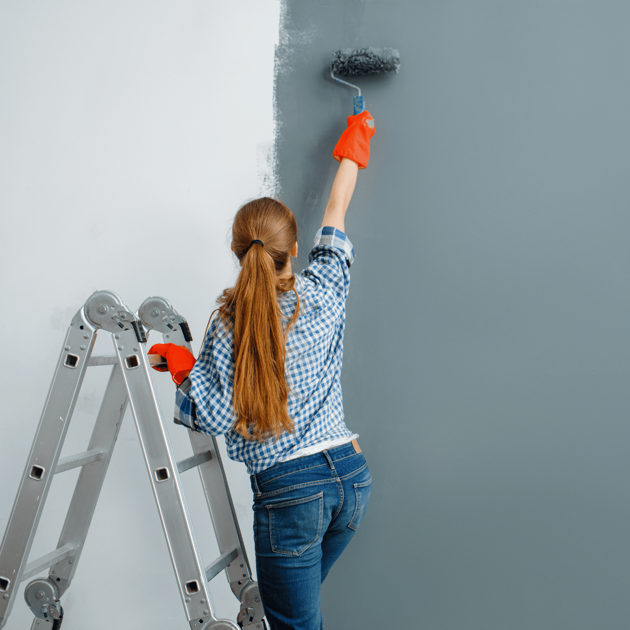 A woman painting a wall with a roller