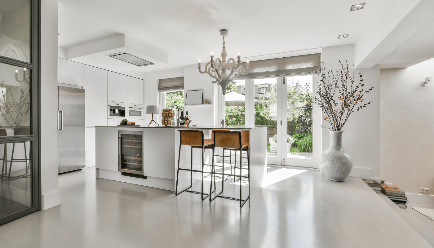 A kitchen with a large island , stools and a chandelier.