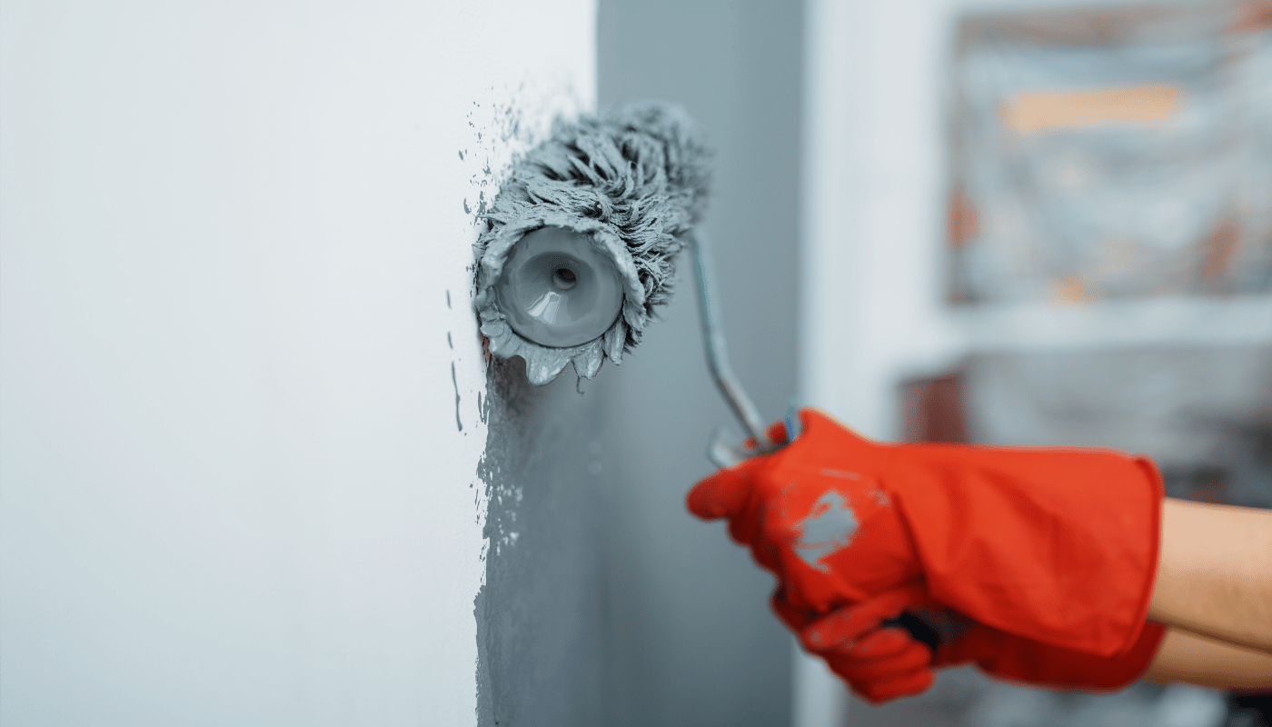 A person is painting a wall with a paint roller.