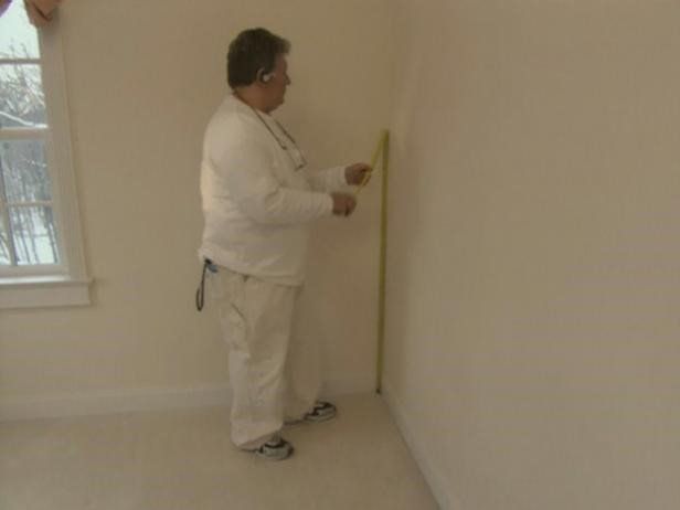 A man measuring a wall for wallpaper