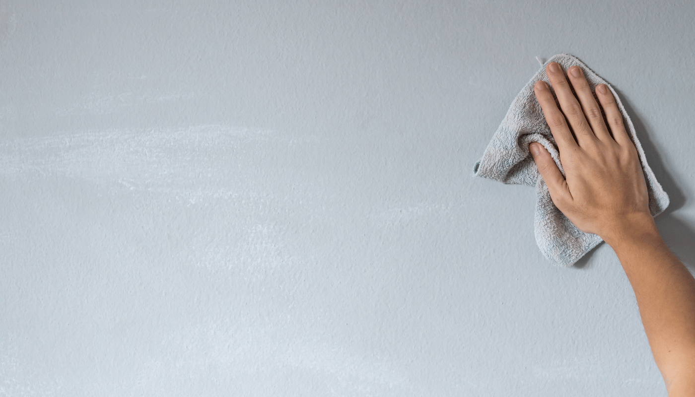 A person is cleaning a wall with a towel.