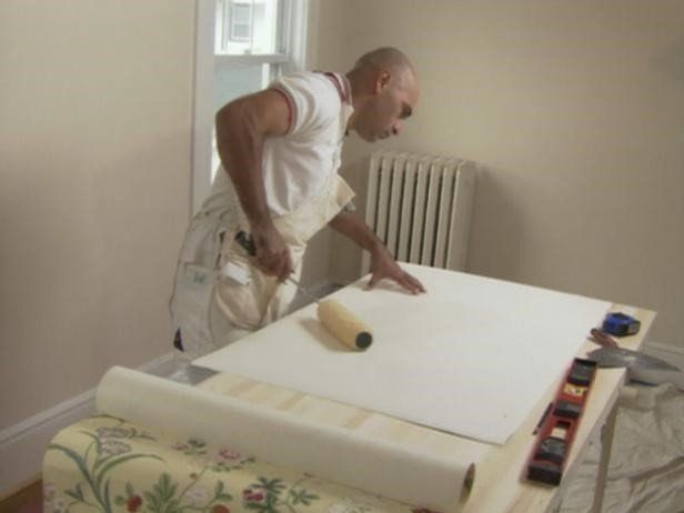 Man rolling glue onto wallpaper