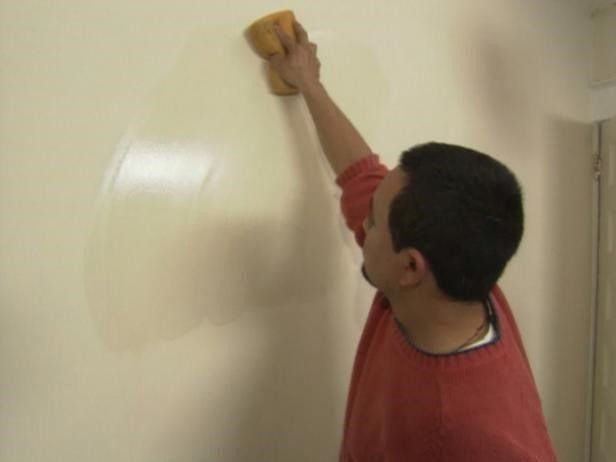 A tradesman sanding a wall