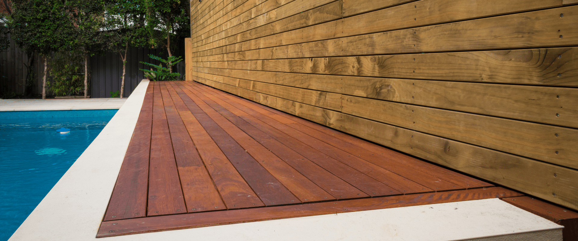 There is a wooden deck next to a swimming pool.