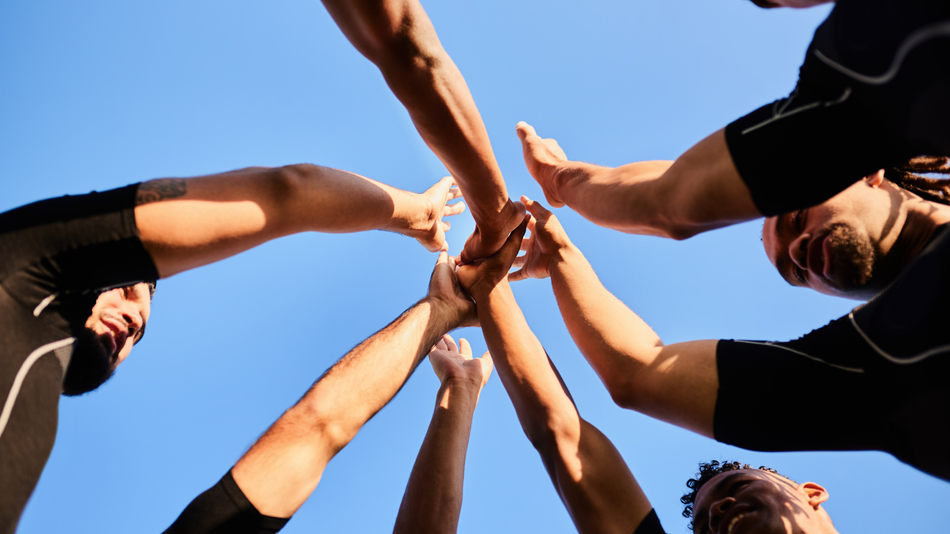 A group of people are putting their hands together in a circle.