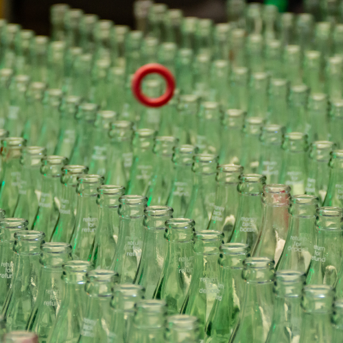 A bunch of green bottles with a red circle in the middle.