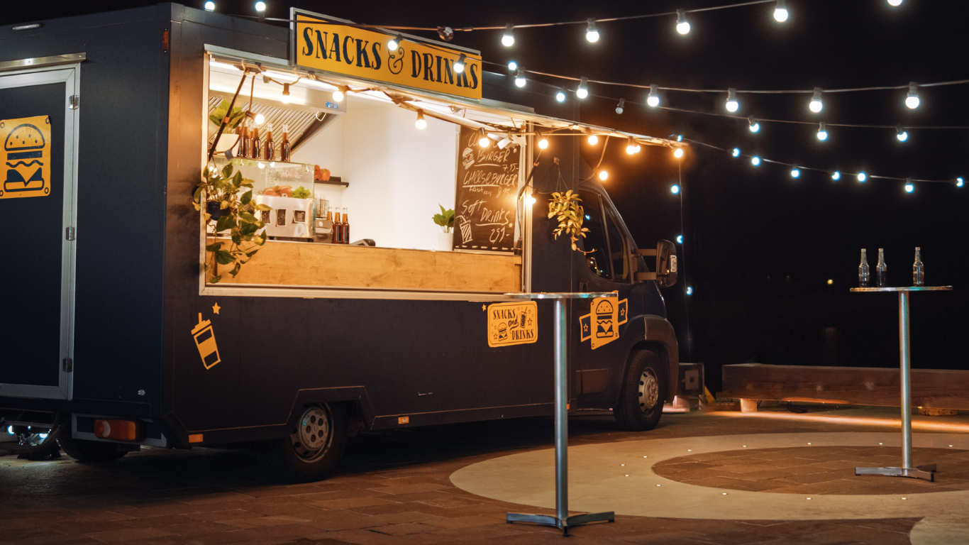 A food truck is parked in a parking lot at night.