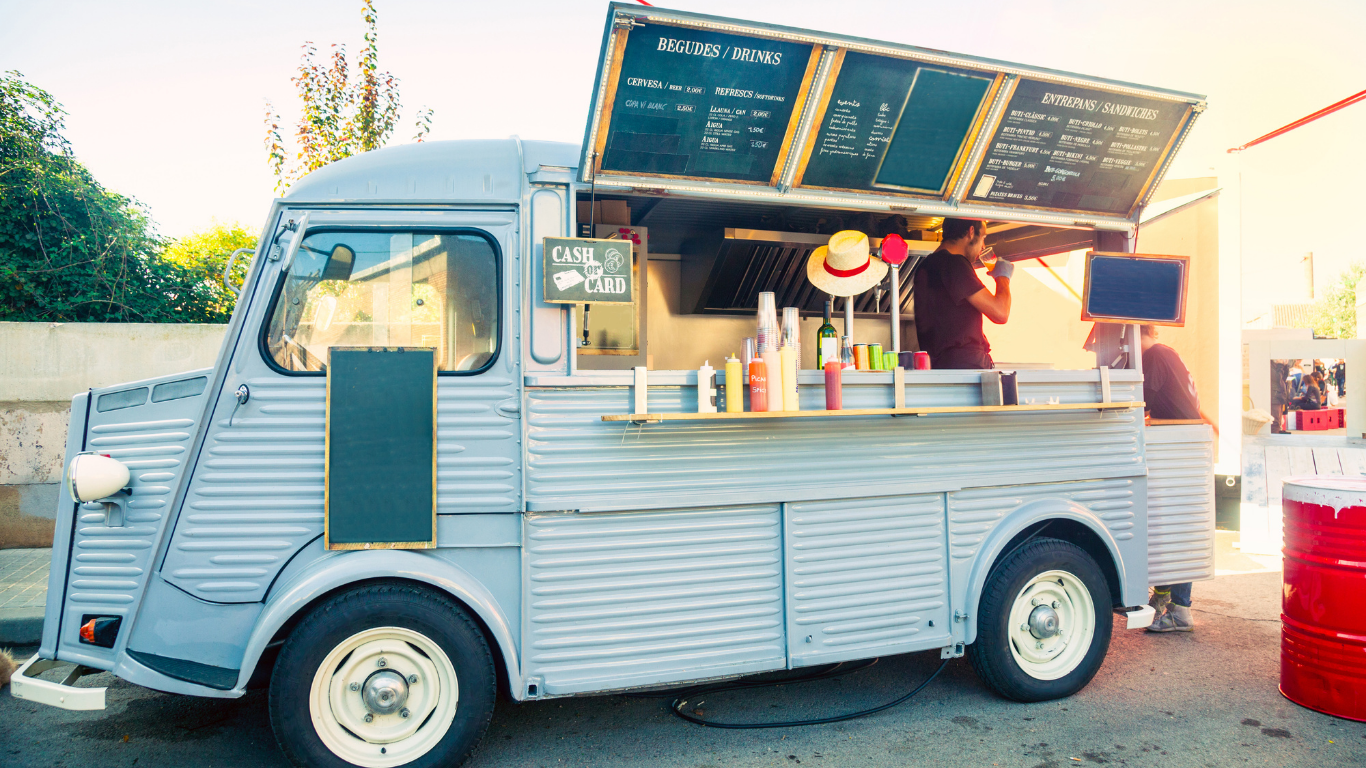 A food truck is parked in a parking lot with the door open.