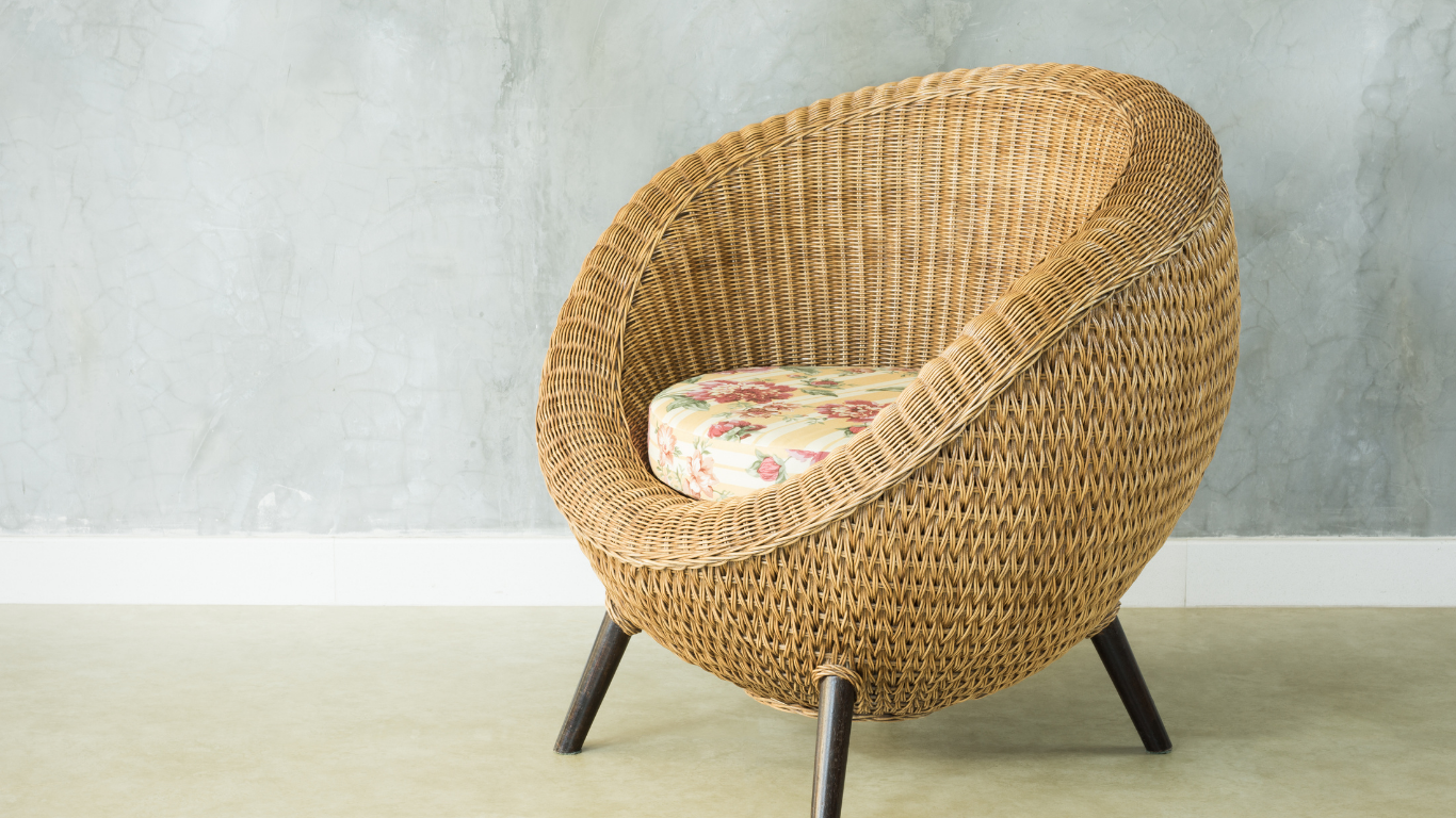 A wicker chair with a floral cushion is sitting on a carpet in a room.