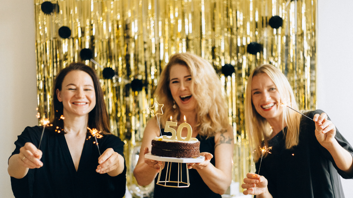Three women are holding sparklers and a birthday cake.