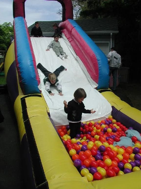 Children are playing on an inflatable slide in a ball pit