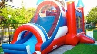 A red , white and blue bouncy house with a slide attached to it.