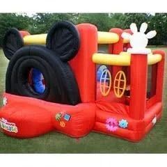 A mickey mouse bouncy house is sitting on top of a lush green field.