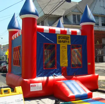A red and blue bouncy house with a sign that says 