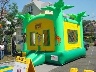 A green and yellow bouncy house with a sign in front of it