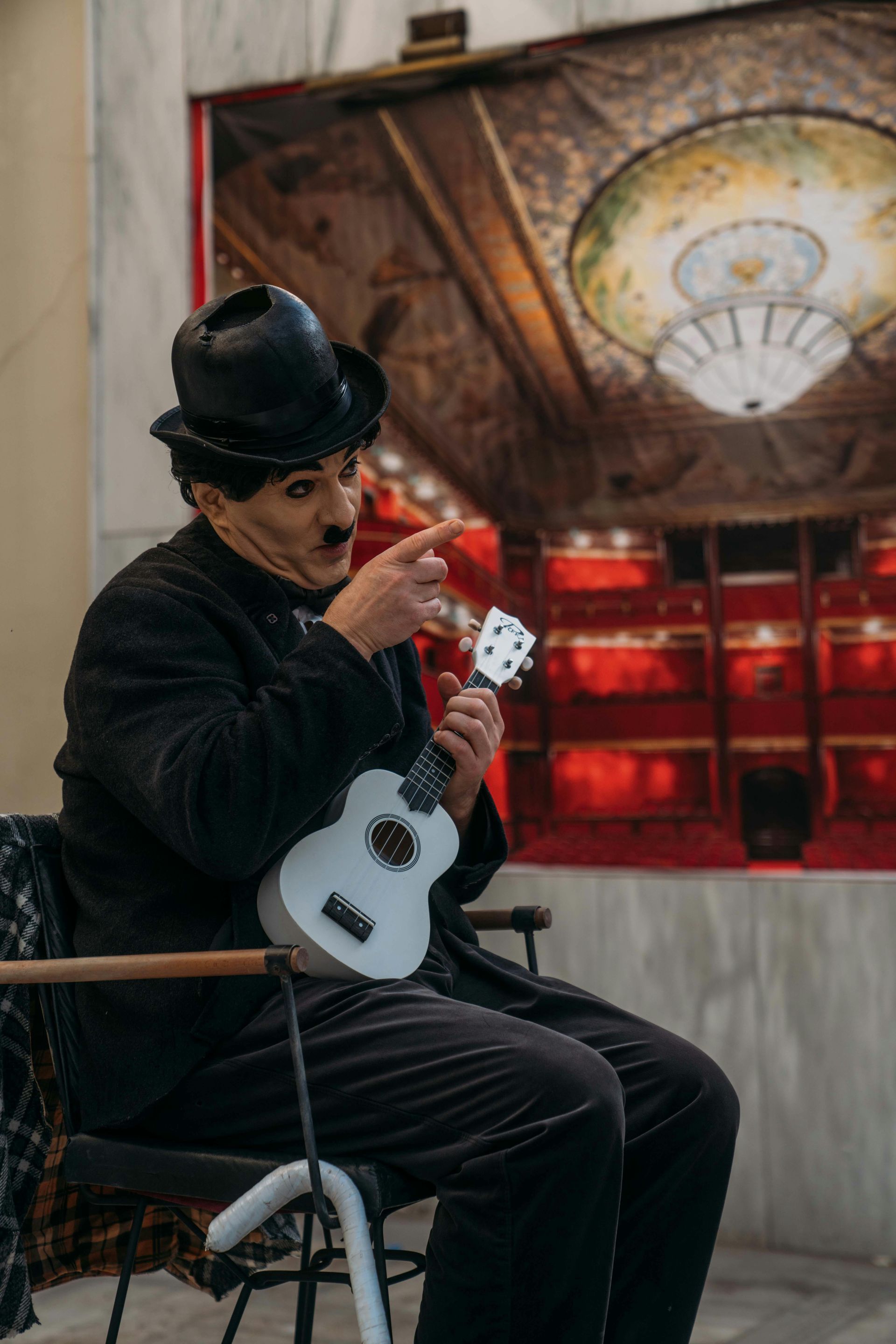 A man in a hat is sitting in a chair playing a guitar.