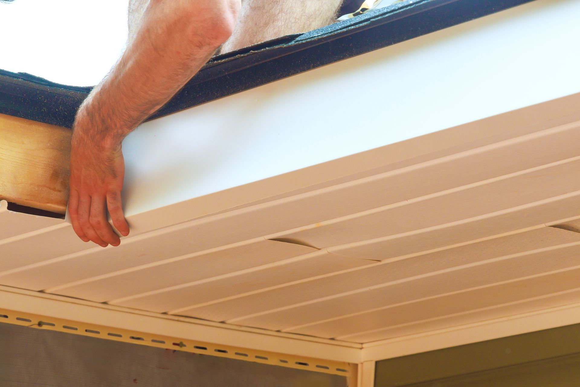 Hand reaching up to adjust white ceiling panels indoors