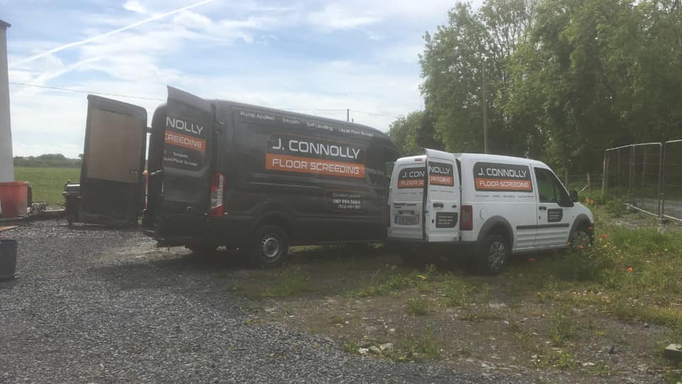 Two vans are parked next to each other in a gravel lot.