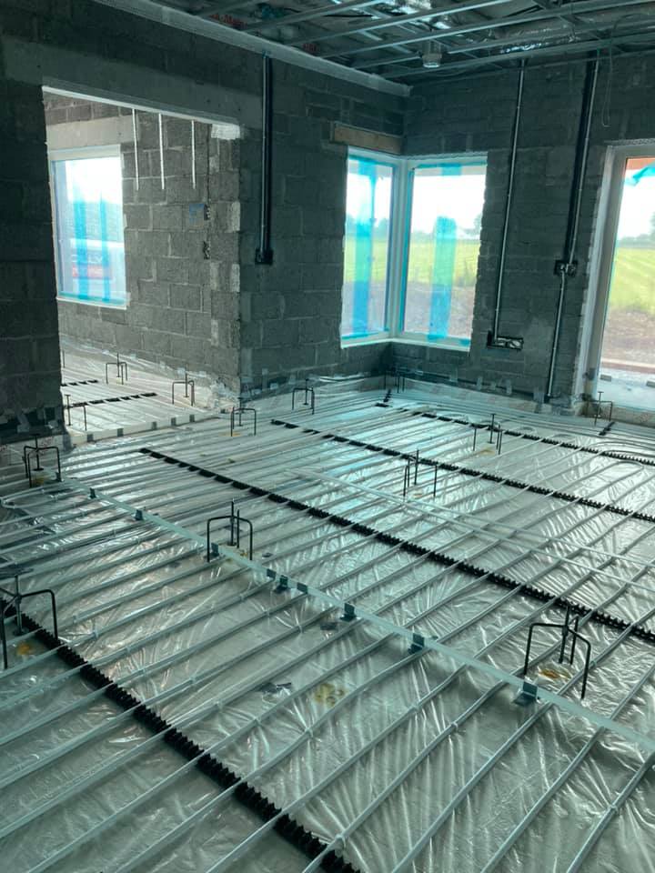 A room under construction with a concrete floor and a lot of windows.
