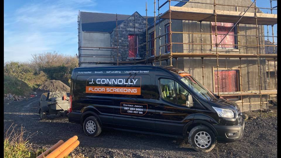 A black van is parked in front of a building under construction.