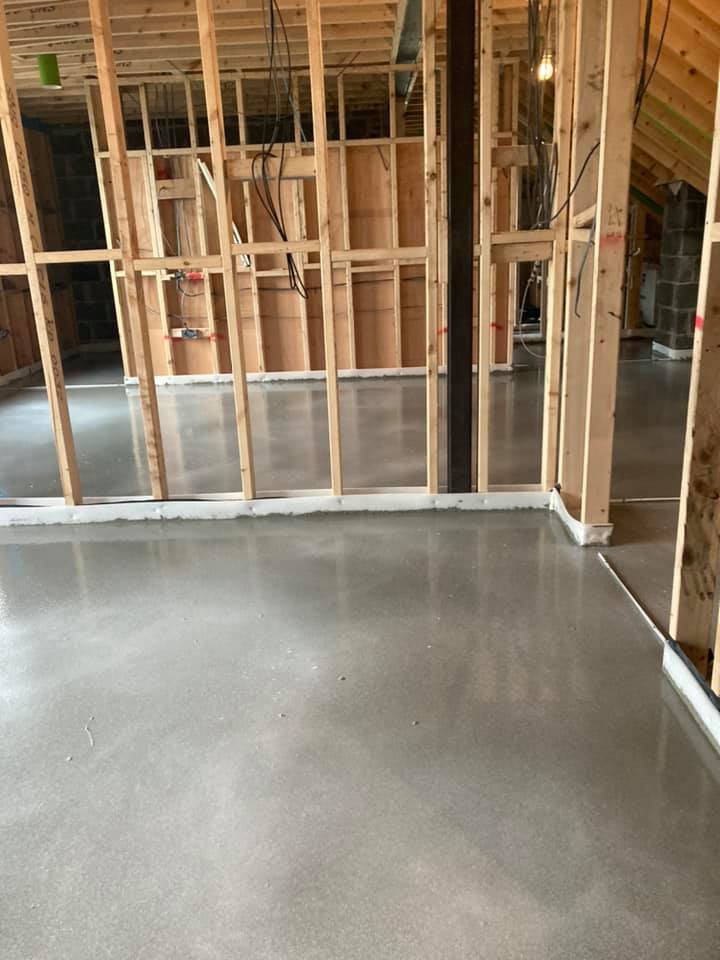 A room with a concrete floor and wooden walls under construction.
