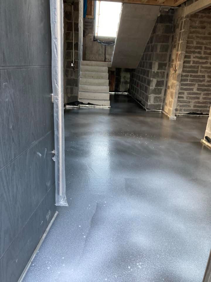 A concrete floor in a basement with a staircase in the background.
