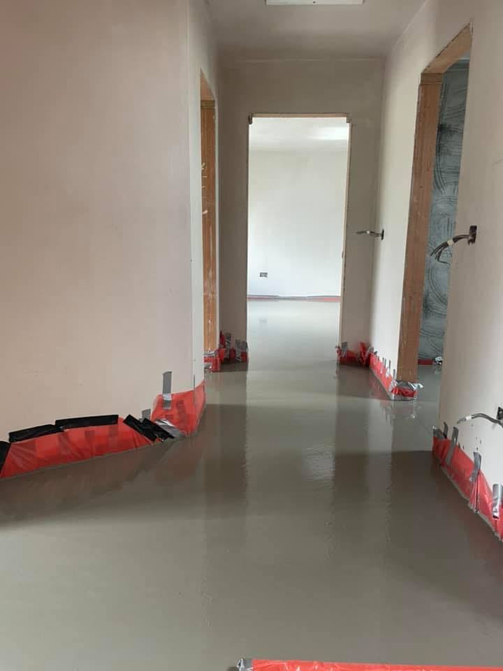 A hallway with a concrete floor in a house under construction.