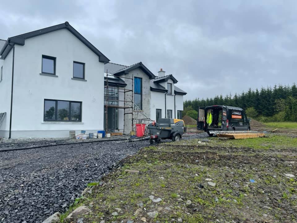A large white house is being built in a field.