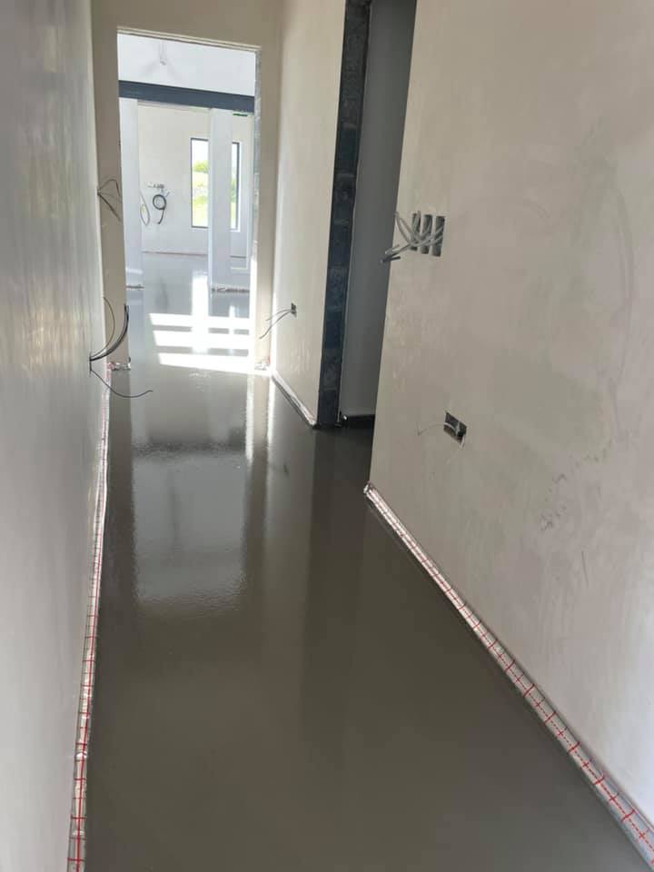 A long hallway with a concrete floor in a house under construction.