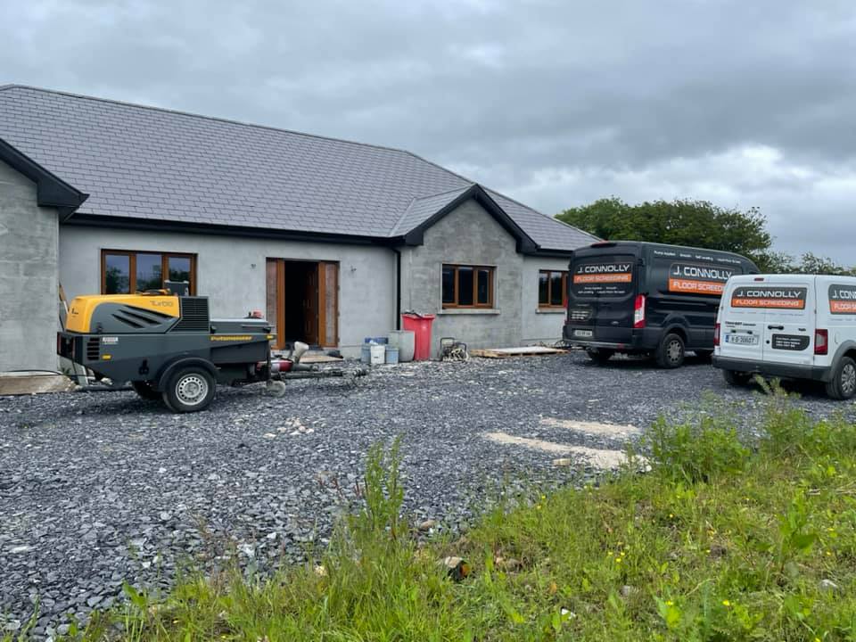 Two vans are parked in front of a house under construction.