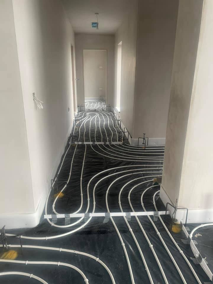 A hallway with a black floor and white pipes on it.