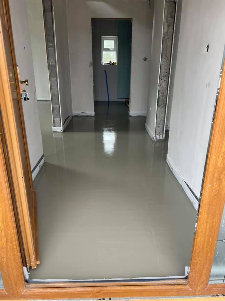 A hallway with a wooden door and a concrete floor.