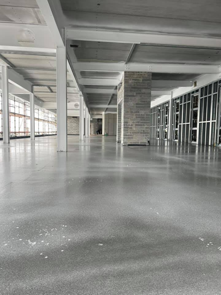 A large empty building with a concrete floor and a lot of windows.