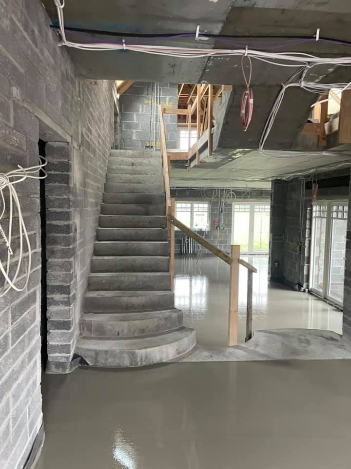 A staircase in a building under construction with a wooden railing.