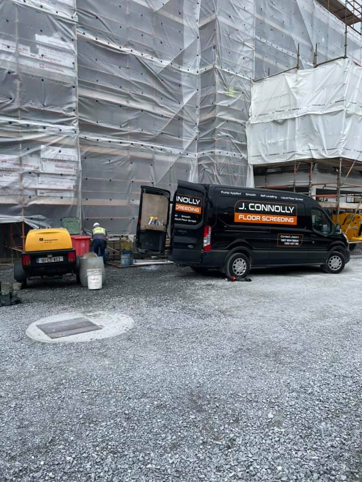Two vans are parked in front of a building under construction.
