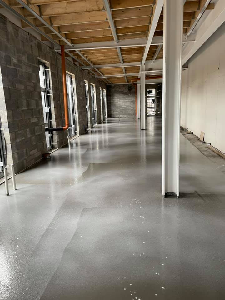 A long hallway in a building with a concrete floor and columns.